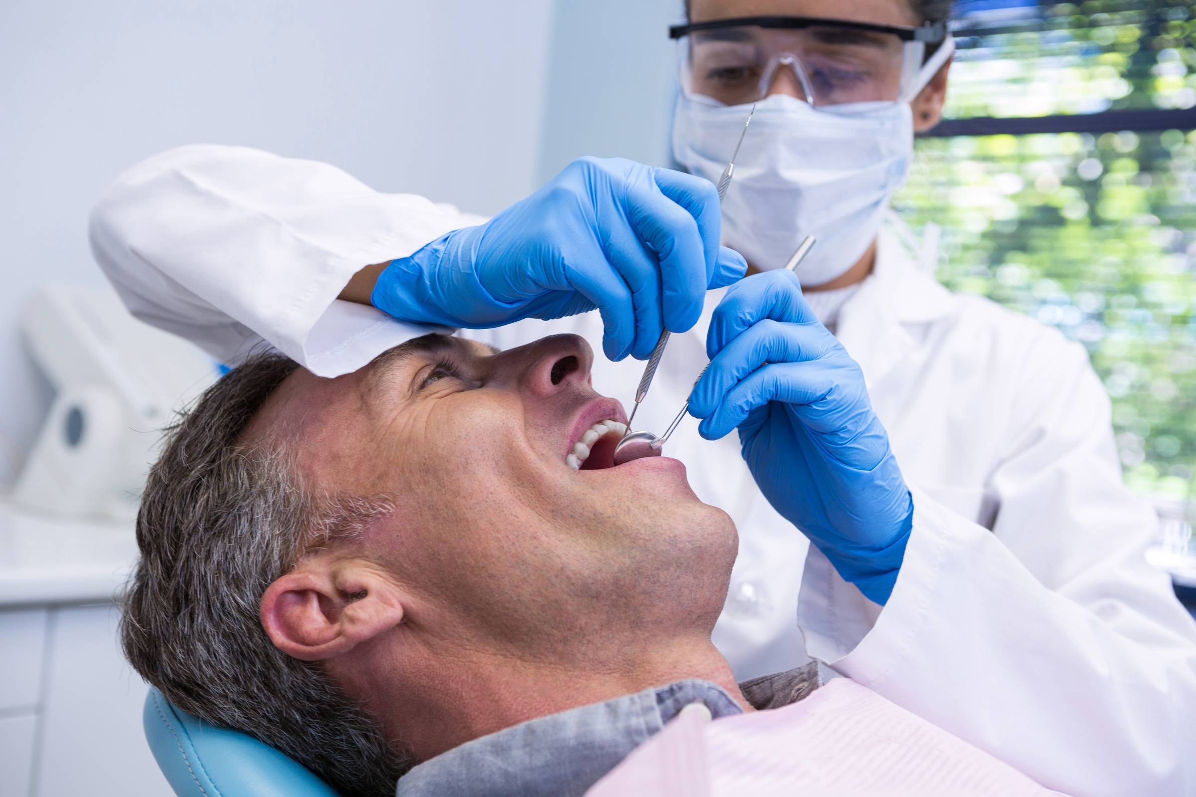 Dental professional smiling in front of dental equipment.