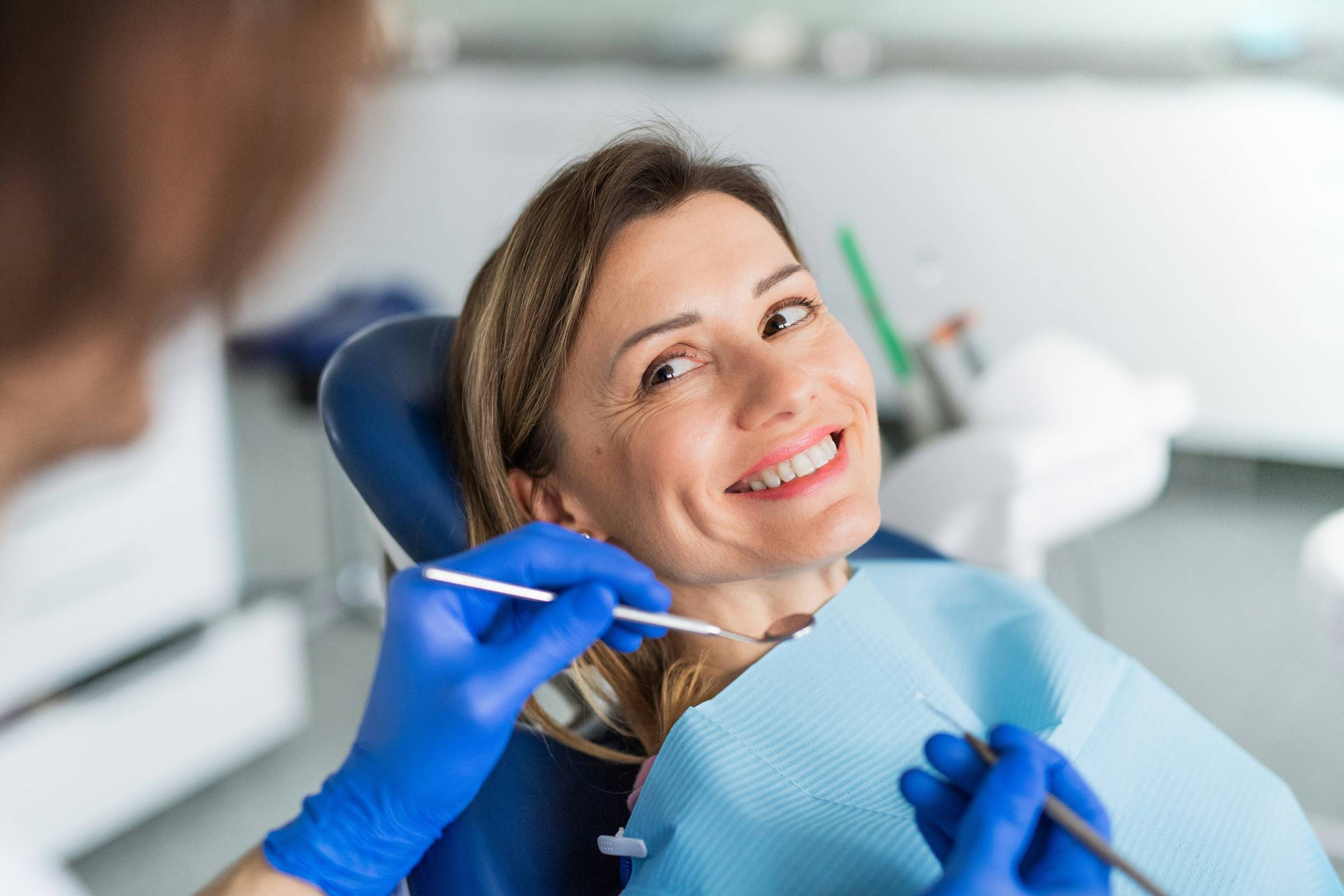 Dental professional smiling in front of dental equipment.